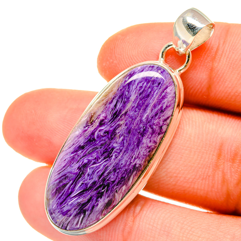 Charoite pendant close-up with oval purple stone, silver tone frame and bail.