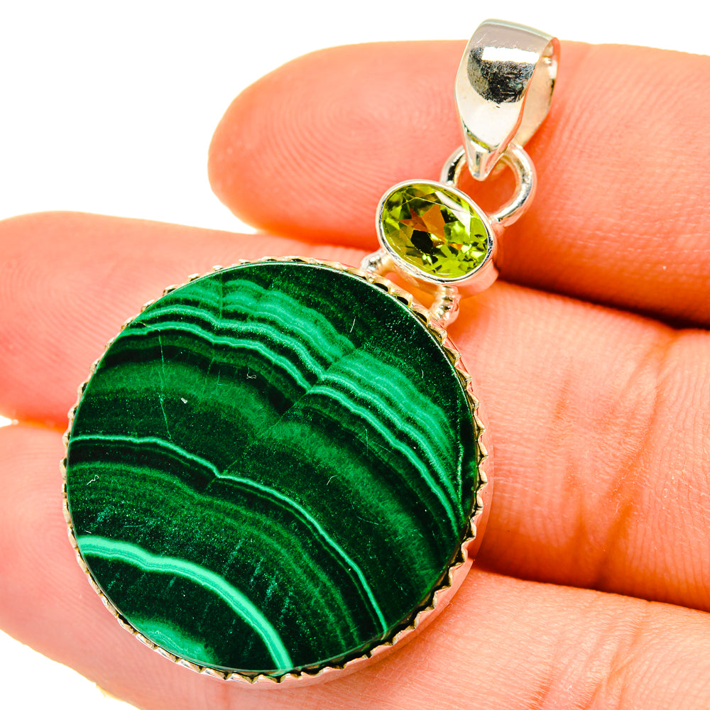 Green malachite round pendant with peridot cabochon and silver bail, close-up.