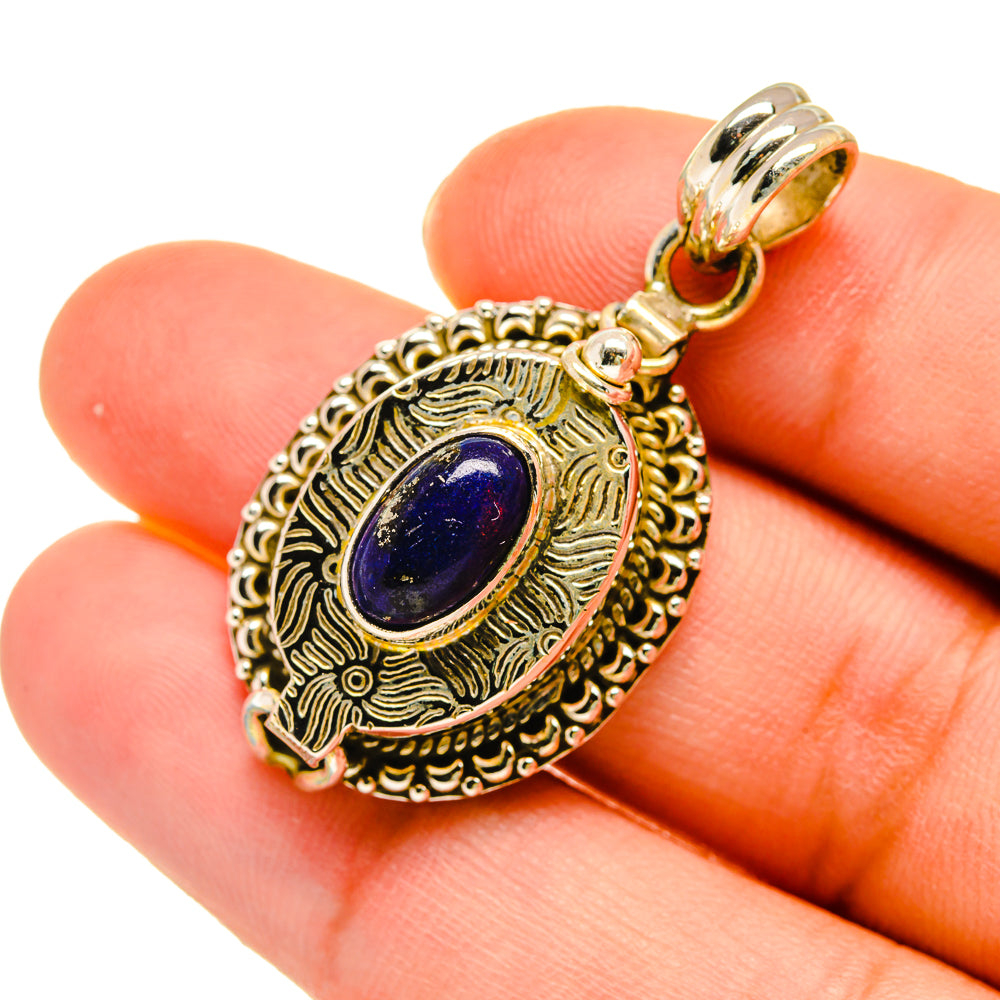 Gold-tone lapis lazuli pendant close-up with oval stone and engraved filigree border