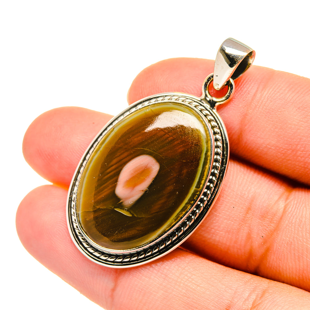 Oval amber jasper pendant in sterling silver filigree bezel with bail, close-up on stone