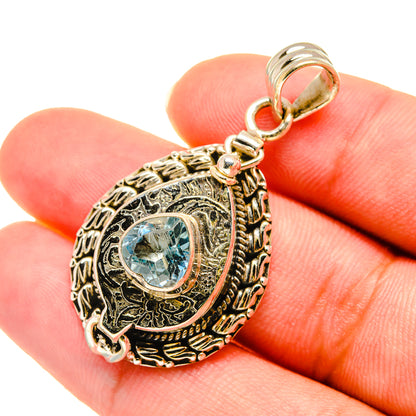 Sterling silver blue topaz pendant close-up with ornate oval setting and bail