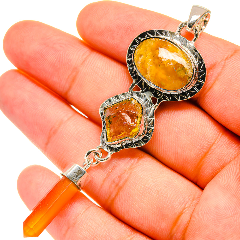 Orange gemstone pendant on silver chain with oval center and crystal point drop