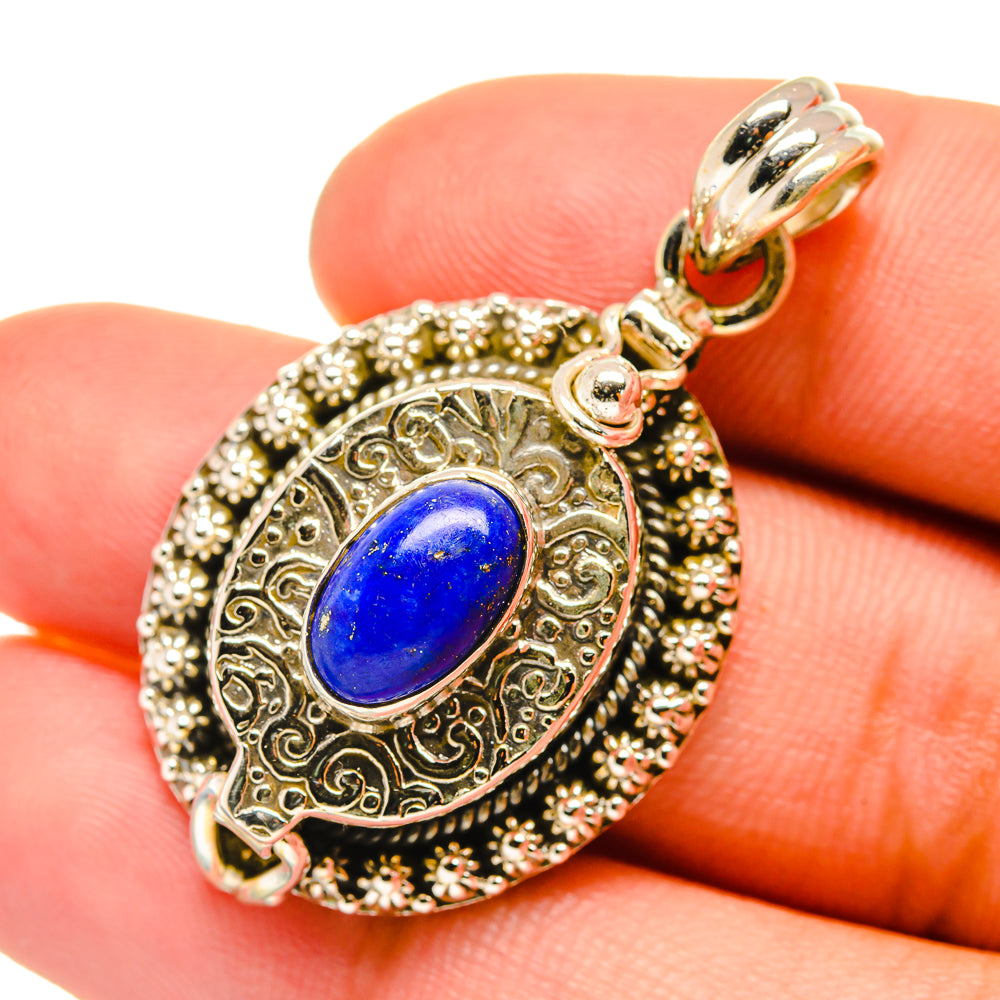 Ornate lapis lazuli oval poison pendant in silver with gold-tone filigree and top loop