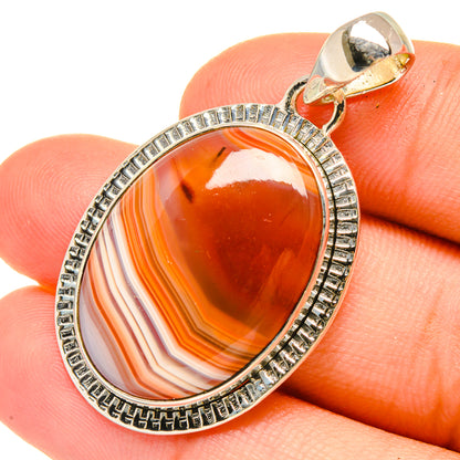 Orange agate oval pendant with sterling silver bezel and bail, close-up view