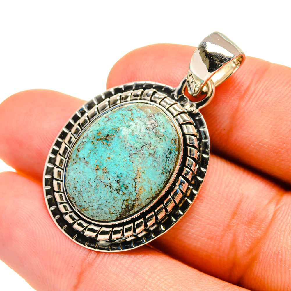 Turquoise oval pendant in sterling silver bezel with ornate border and bail.