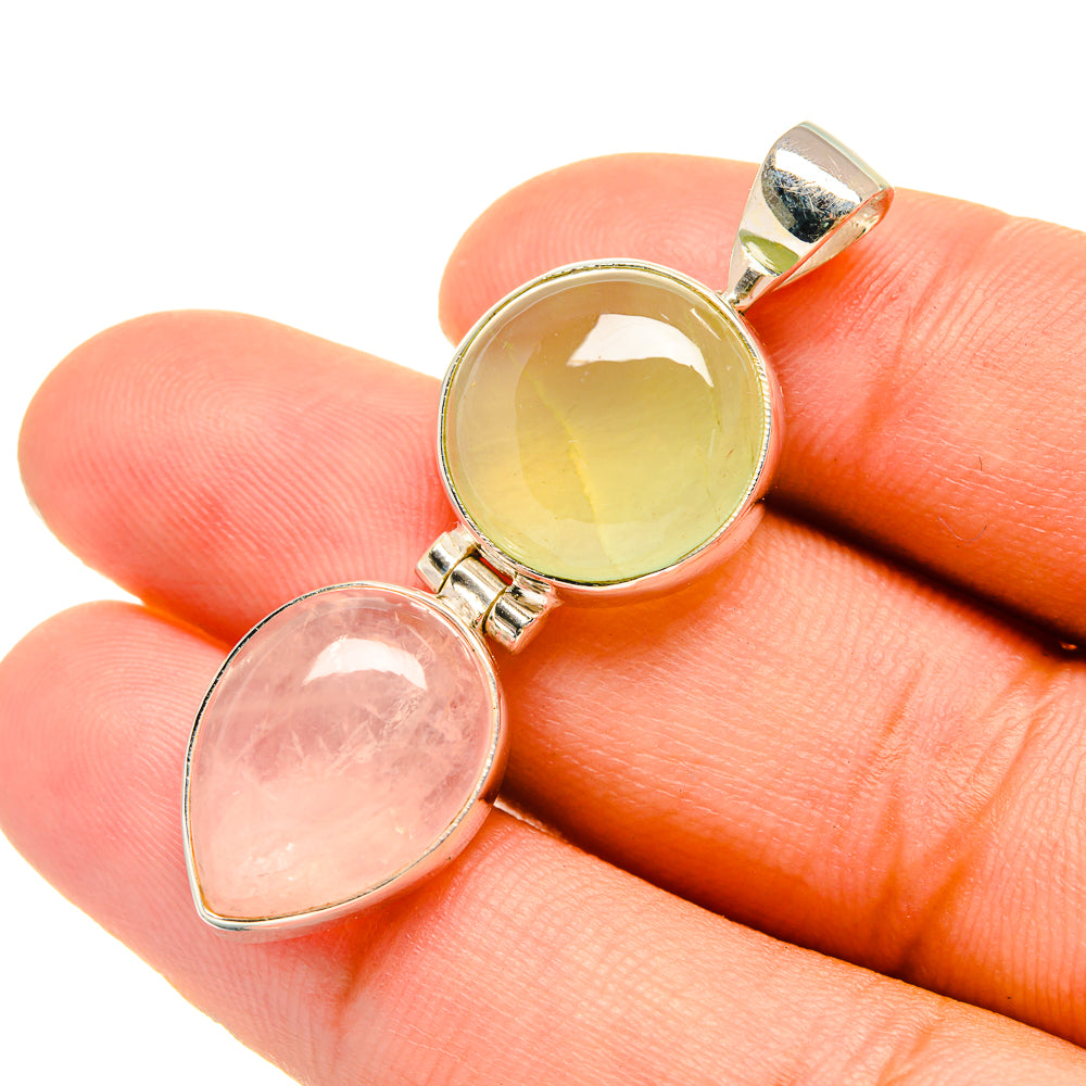 Oval gemstone pendant on fingers, green and pink stones set in silver frames