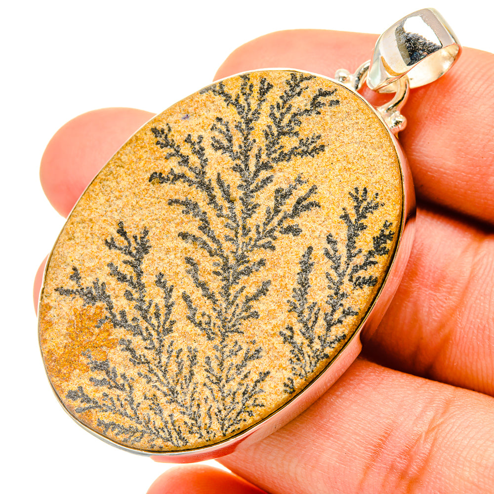 Oval dendrite pendant close-up, yellow-orange stone with black branching pattern, silver bail