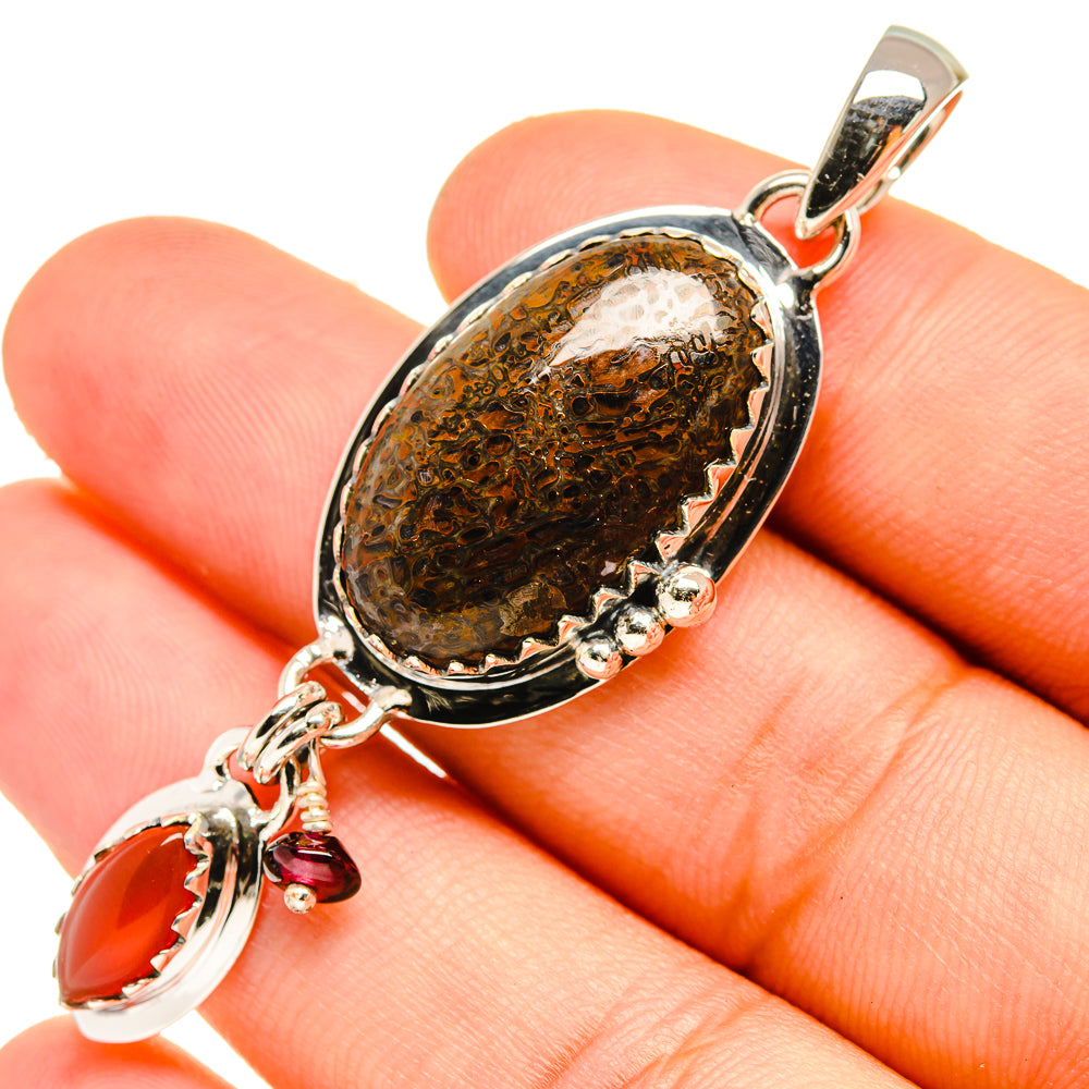Close-up oval brown stone pendant with red drop charm and silver links