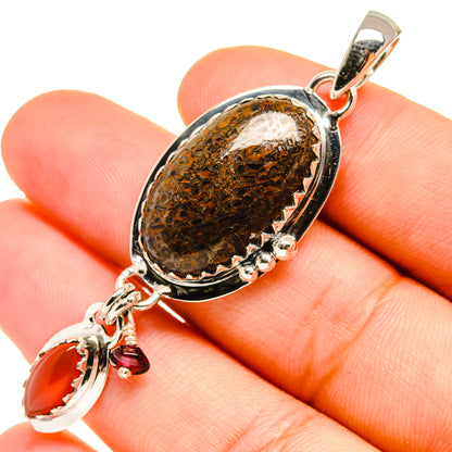 Close-up oval brown stone pendant with red drop charm and silver links
