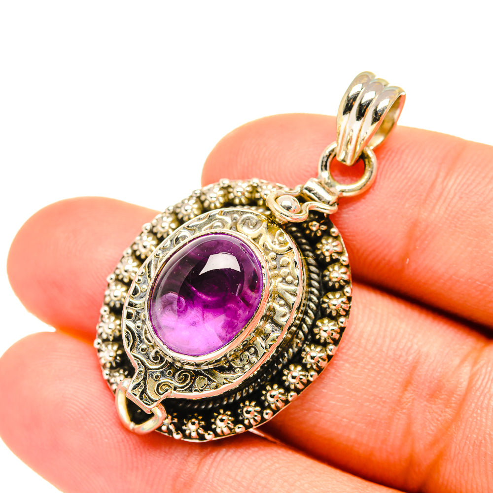 Amethyst oval pendant with ornate silver filigree and gold-tone bail on chain loop