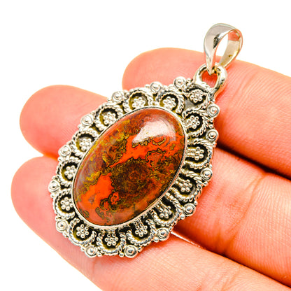 Agate pendant with oval amber-red cabochon and ornate silver filigree frame, loop bail