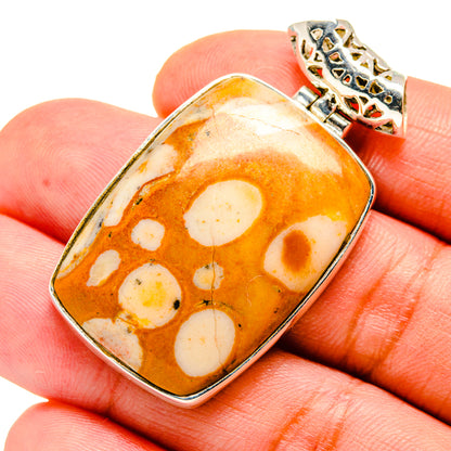 Rectangular orange peanut wood jasper pendant with white spots in silver bezel and ornate top