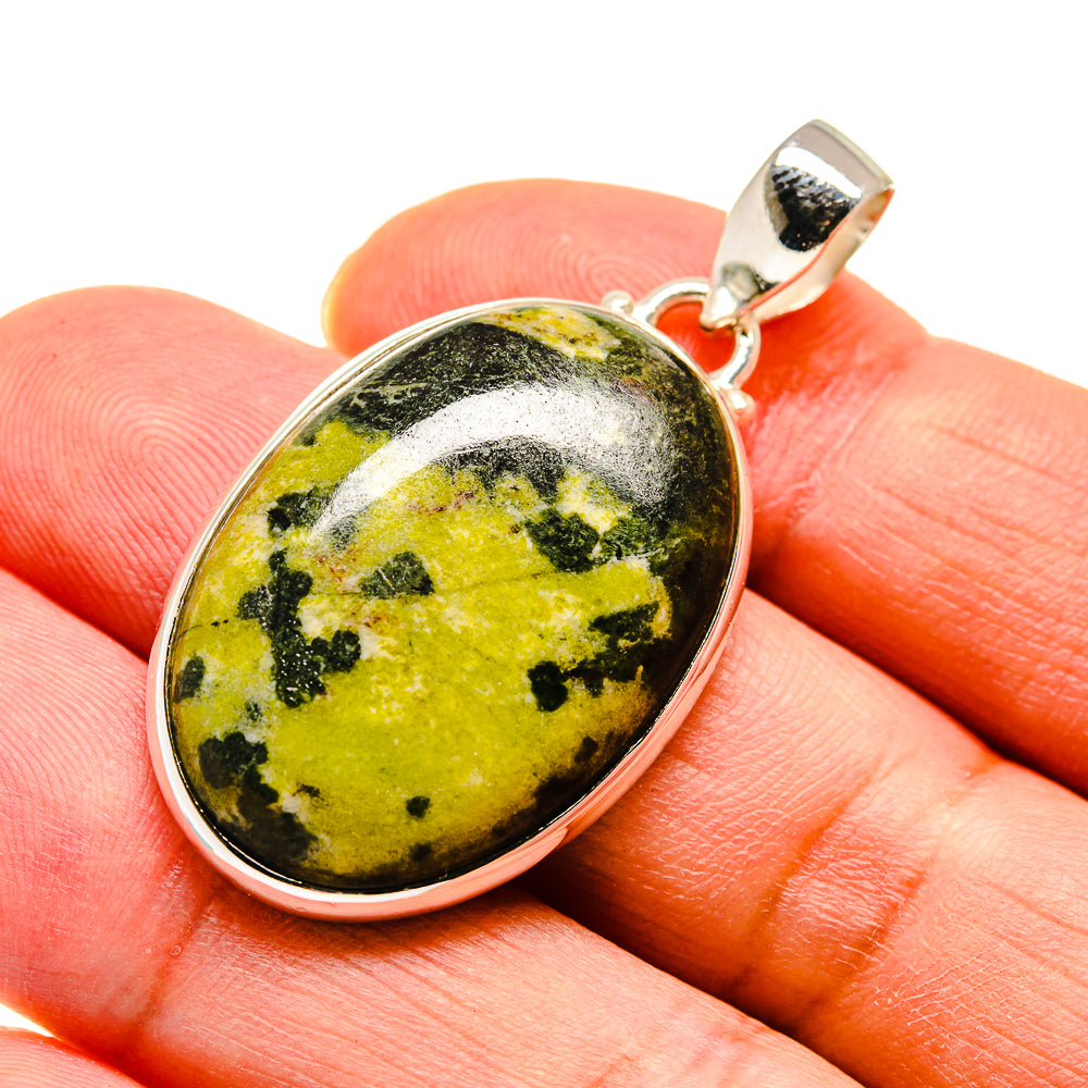 Oval green and yellow jasper sterling silver pendant shown on a finger