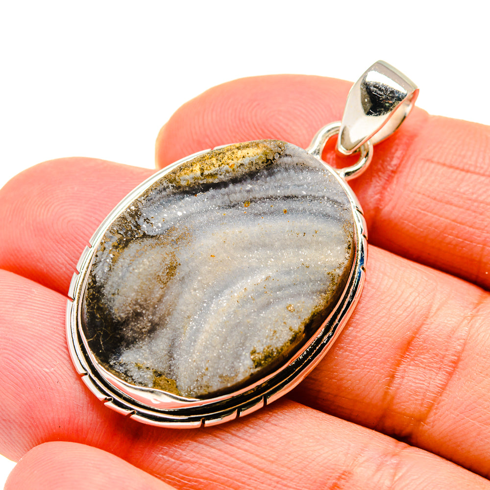 Close-up of oval sterling silver drusy pendant with gold and dark speckled stone bezel