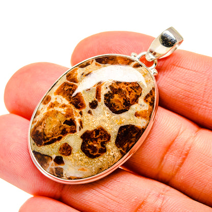 Muscovite pendant on fingers, round sterling silver bezel with mottled amber stone