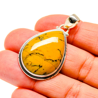 Picture jasper teardrop pendant with silver bezel and gold bail, shown in hand