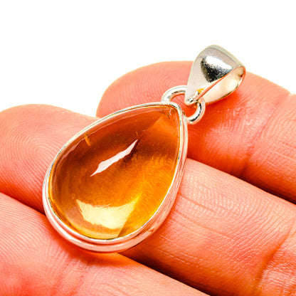 Pear-shaped citrine pendant in 925 sterling silver on a close-up finger