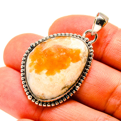 Oval orange and cream gemstone pendant in silver setting with textured edge and bail