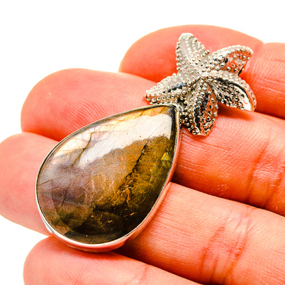 Labradorite teardrop pendant with starfish bail in 925 sterling silver, view on hand