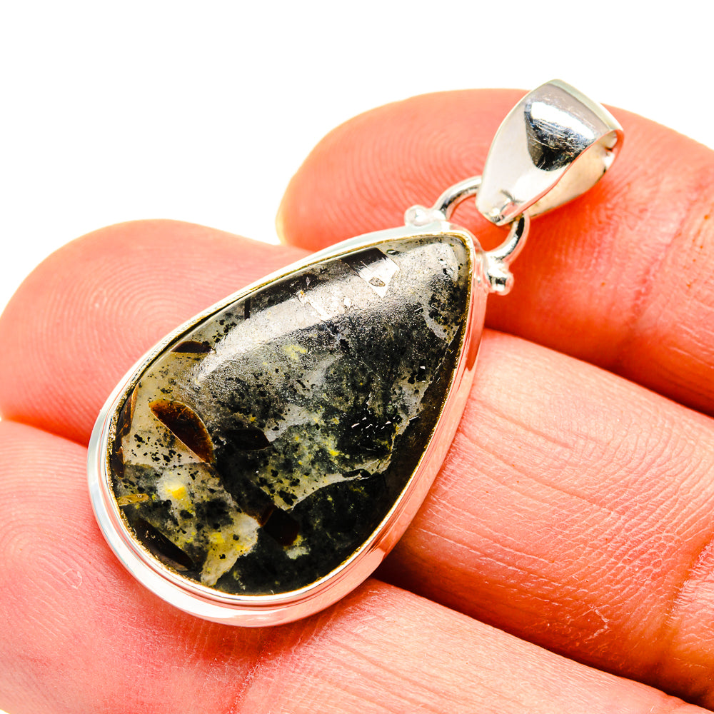 Astrophyllite teardrop pendant with silver bezel and clasp, on fingertip