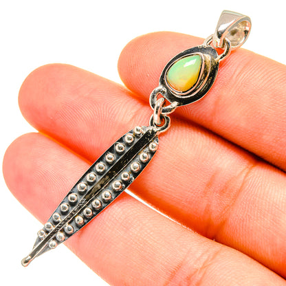 Sterling silver opal pendant on finger, green-yellow teardrop stone with black textured bar