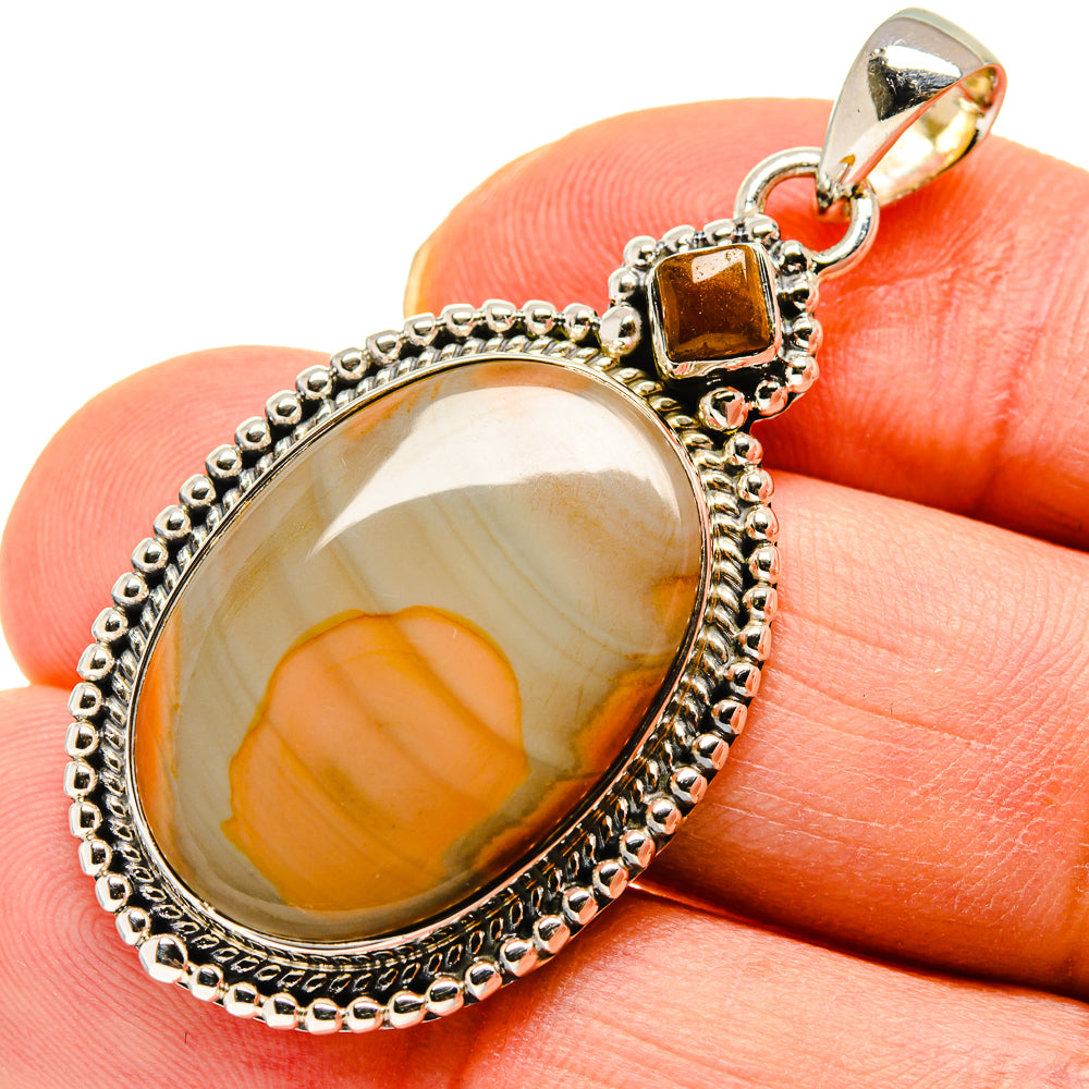 Gold-tone 925 sterling silver pendant with oval orange cabochon, shown on finger