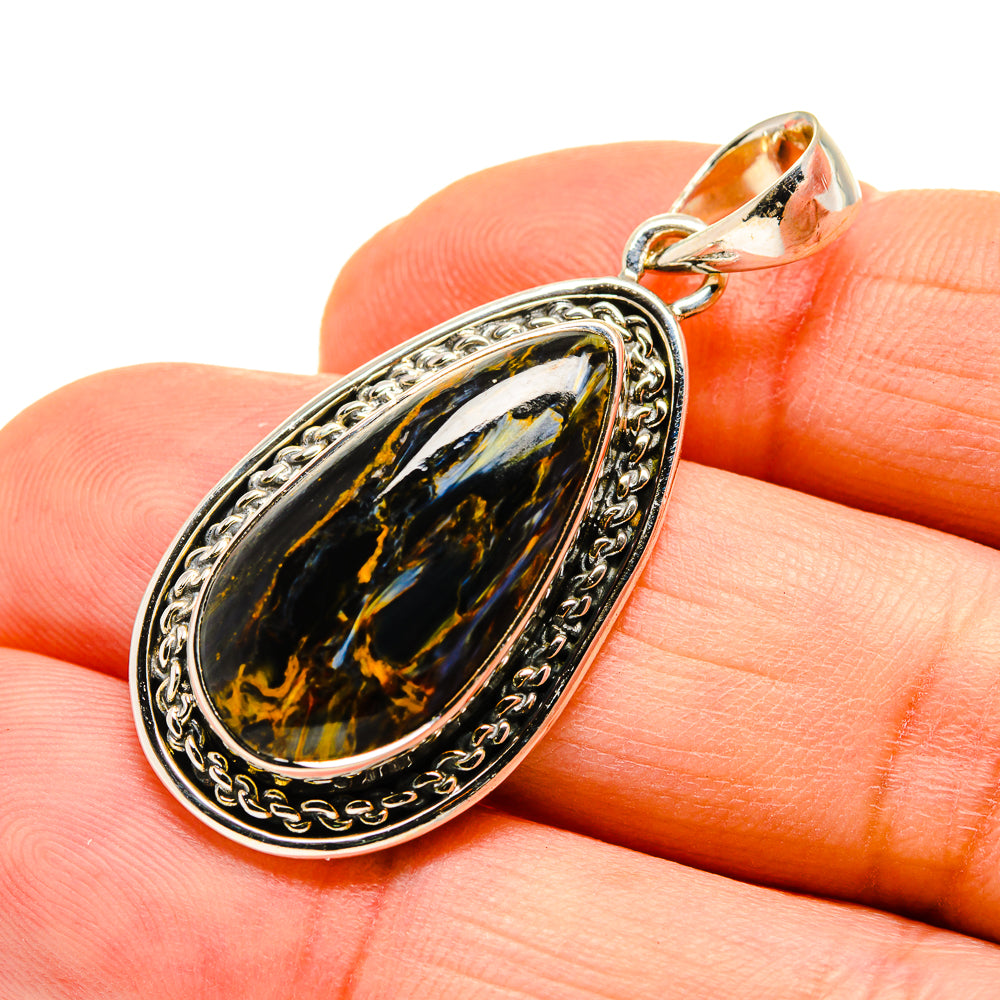 Pietersite teardrop pendant with ornate border and silver bail, glossy blue-gold stone