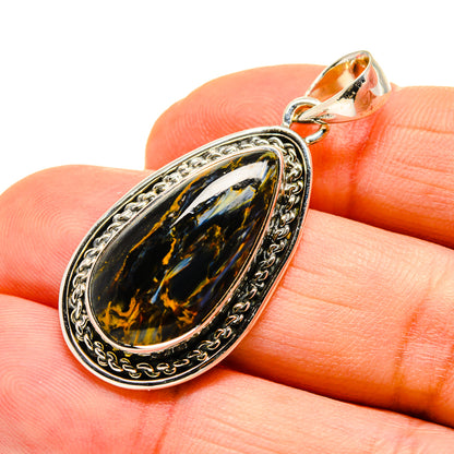 Pietersite teardrop pendant with ornate border and silver bail, glossy blue-gold stone