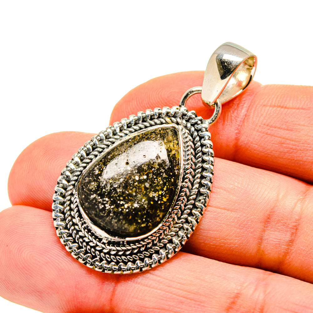 Black agate oval pendant with ornate silver rope border, close-up on finger