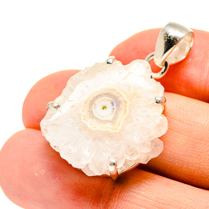 White solar quartz slice pendant with silver prongs, held in hand