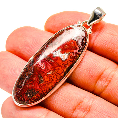 Oval red crazy-lace agate pendant in silver bezel with bail, close-up