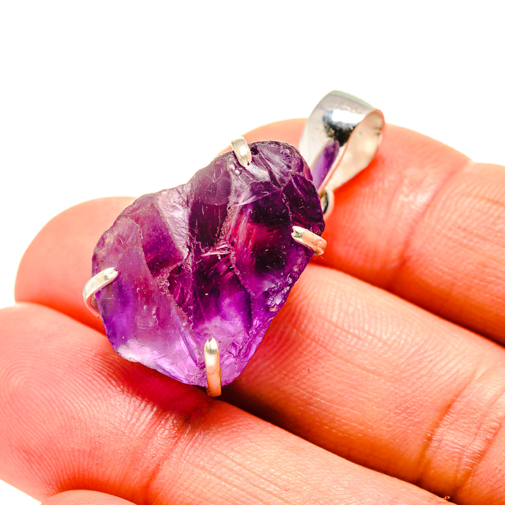 Rough amethyst crystal pendant with silver prongs on purple faceted stone