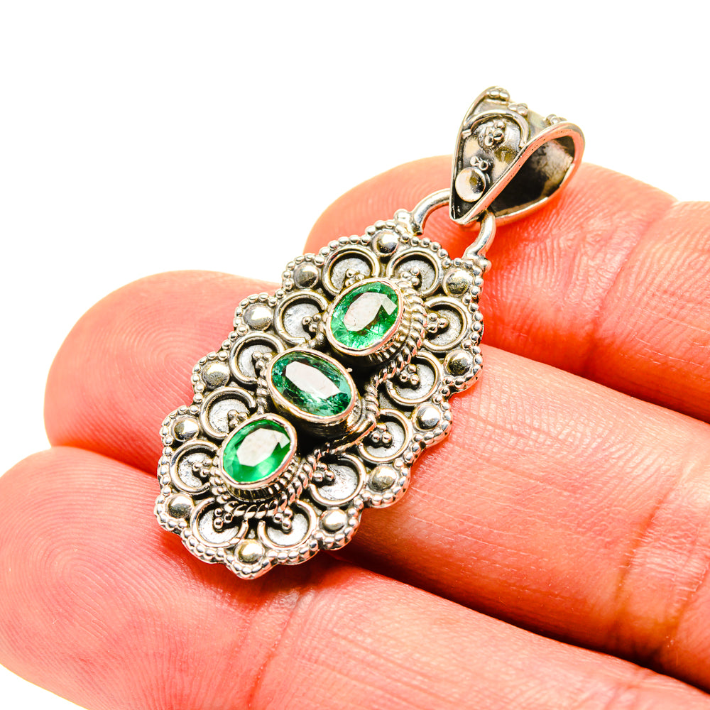 Green emerald pendant with ornate silver setting and three oval stones, gold-tone bail