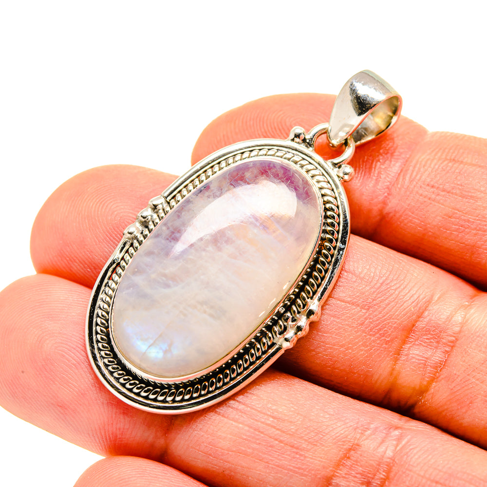 Oval moonstone pendant in silver setting held in fingertips