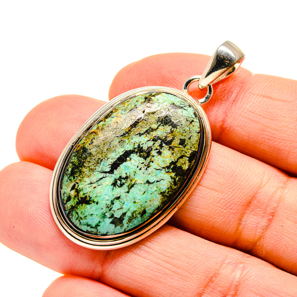 Turquoise oval pendant in sterling silver bezel with top loop bail, on fingertips for scale