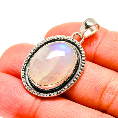 Oval moonstone pendant in silver bezel with textured border and bail, viewed on hand