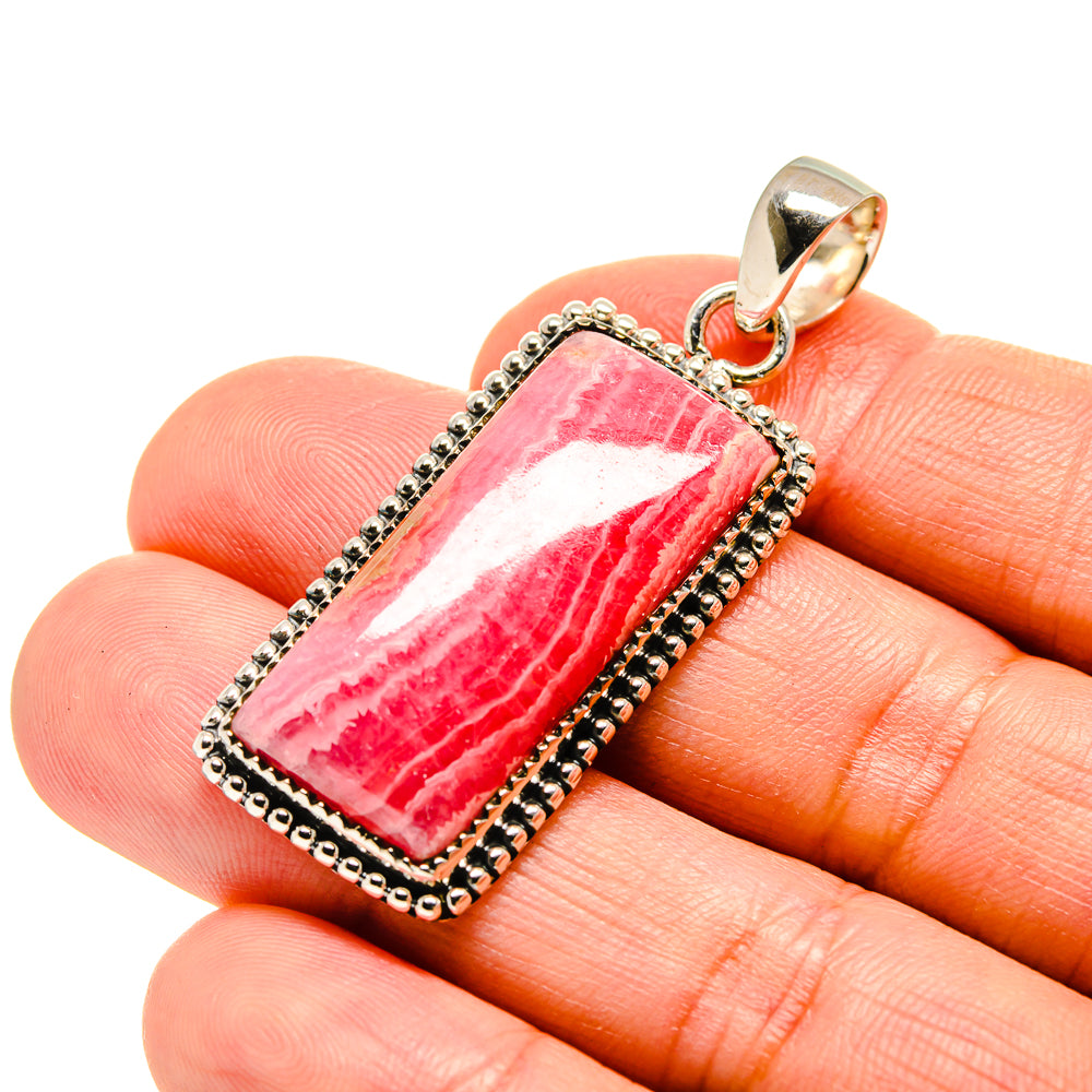 Sterling silver rhodochrosite pendant with pink rectangular striped stone on fingertip