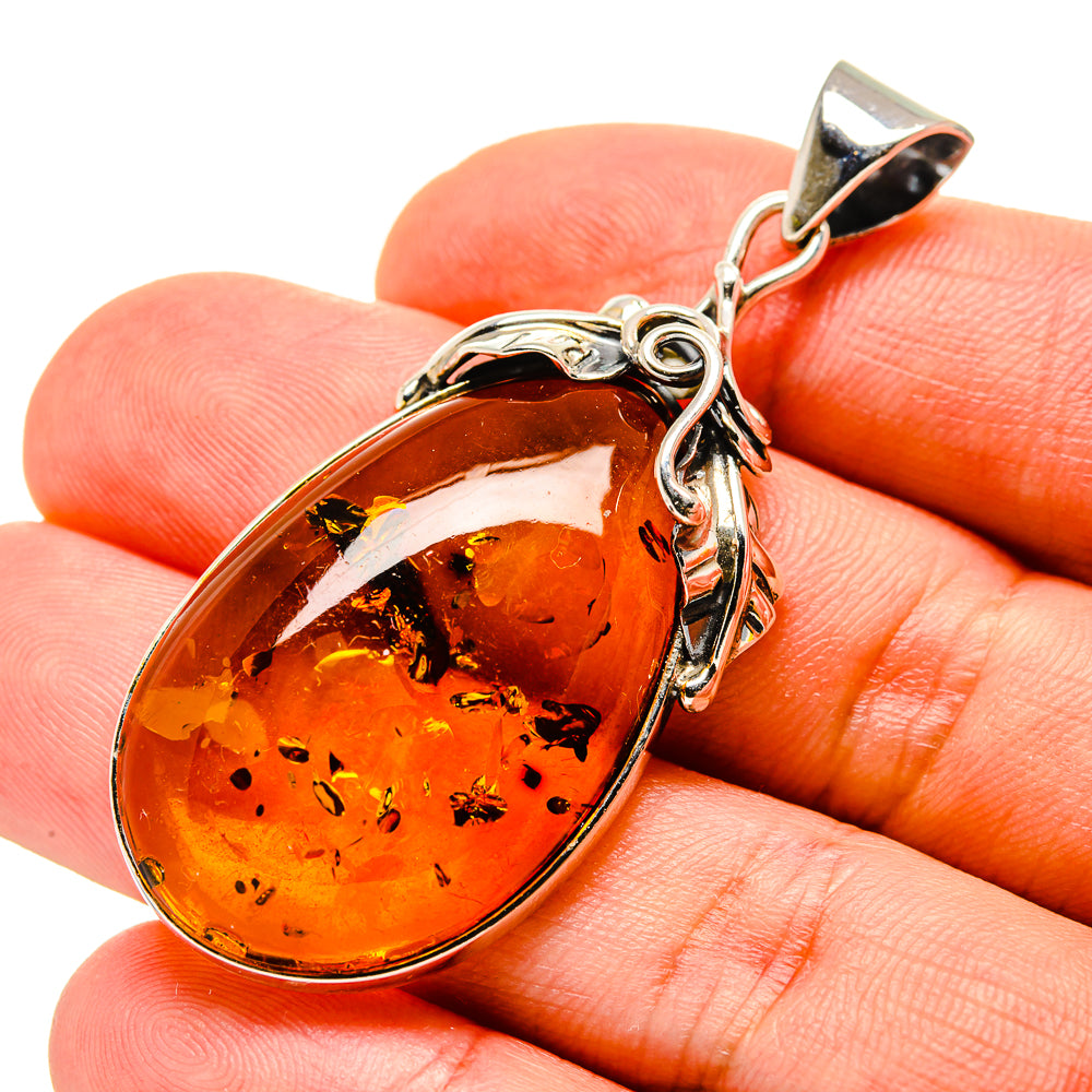 Oval orange-brown Baltic amber pendant in polished 925 sterling silver setting with bail
