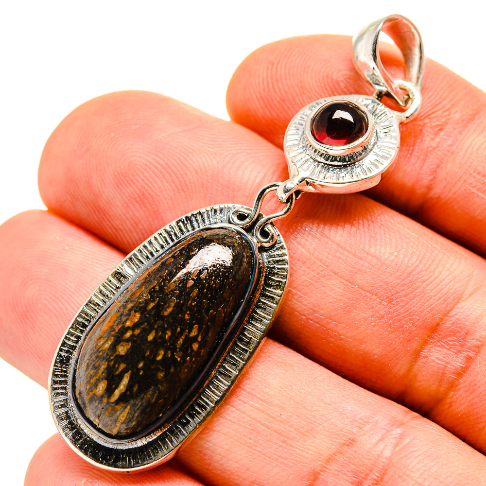 Oval fossil-style stone pendant with red garnet cabochon in sterling silver setting