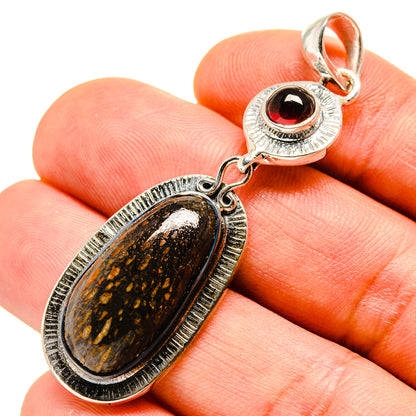 Oval fossil-style stone pendant with red garnet cabochon in sterling silver setting