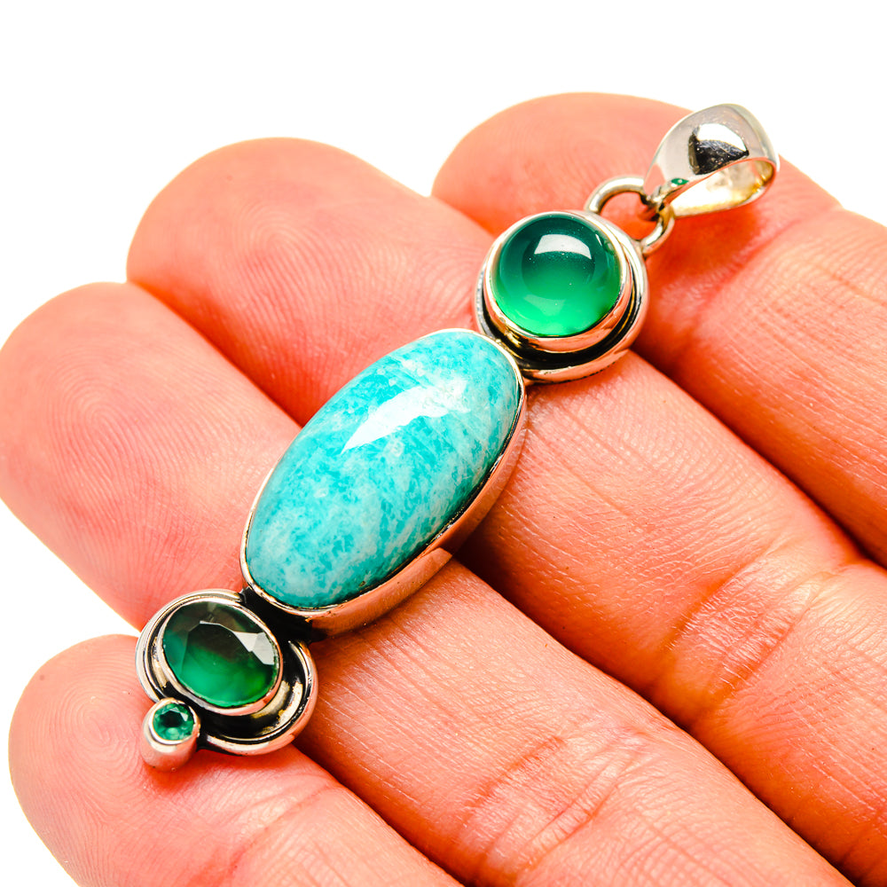 Green onyx and amazonite pendant closeup on hand: oval turquoise stone with round green stones