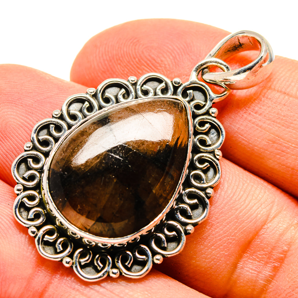 Sterling silver teardrop bail pendant with oval gold-and-black gemstone on hand
