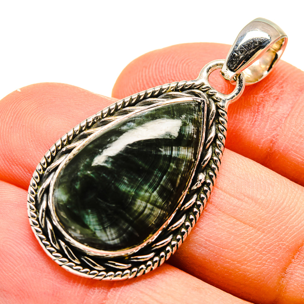 Green teardrop stone pendant in silver bezel with bail, on finger