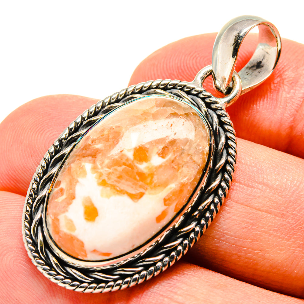 Scolecite pendant close-up with oval orange-and-white stone bezel in silver setting
