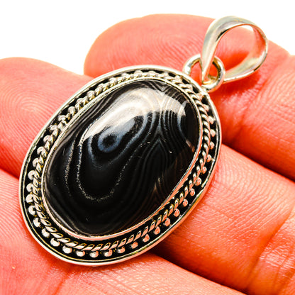 Oval black psilomelane pendant with engraved border and bail in sterling-silver setting