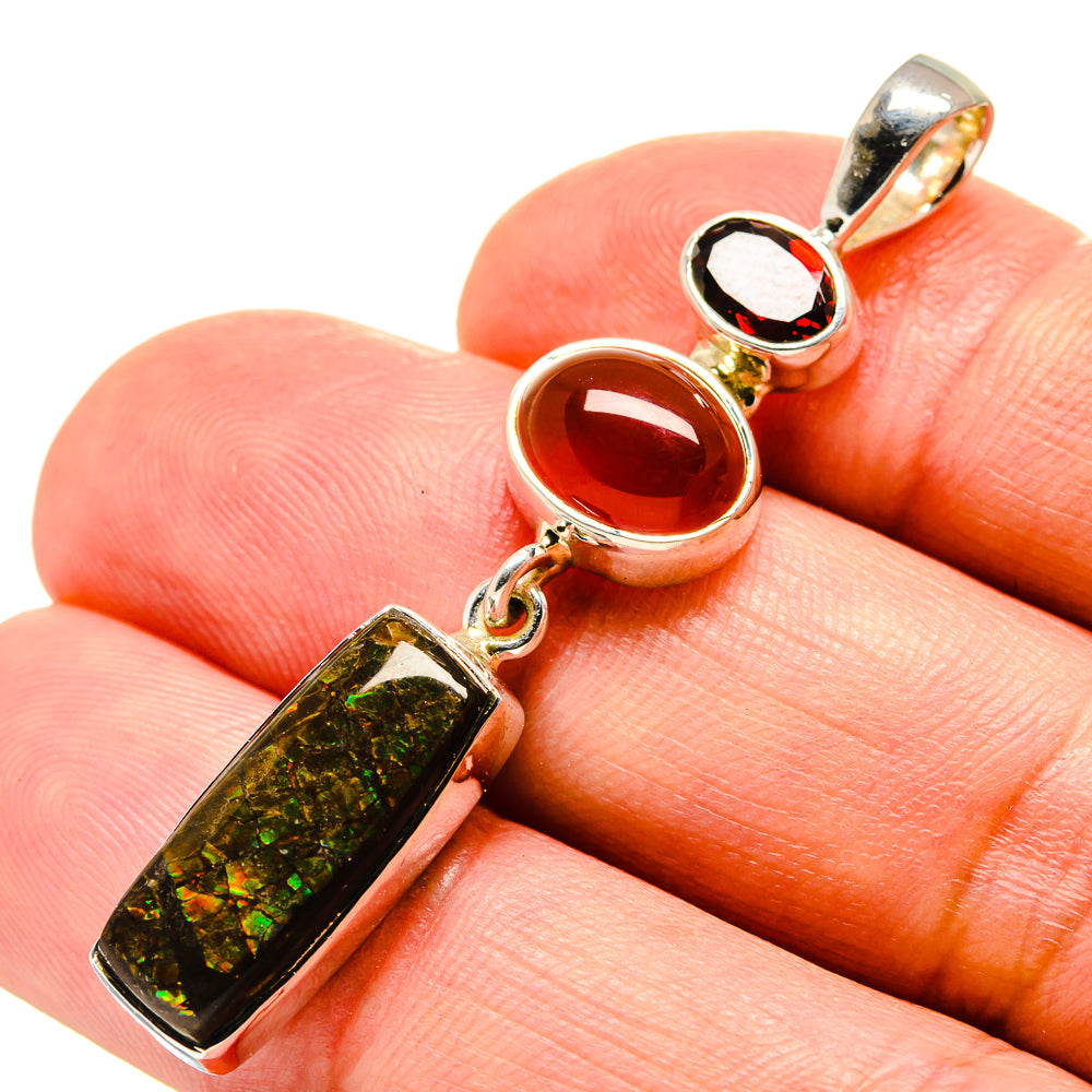 Sterling silver pendant with rectangular iridescent green stone and red round stone, close-up