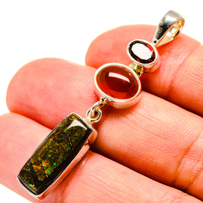 Sterling silver pendant with rectangular iridescent green stone and red round stone, close-up