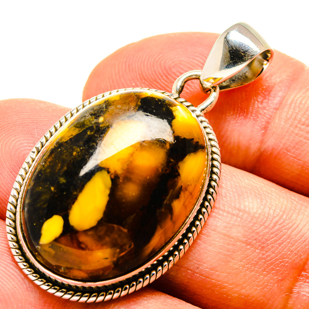 Peanut wood jasper pendant on finger, 925 sterling silver bail, oval yellow and amber