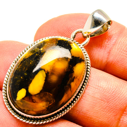 Peanut wood jasper pendant on finger, 925 sterling silver bail, oval yellow and amber