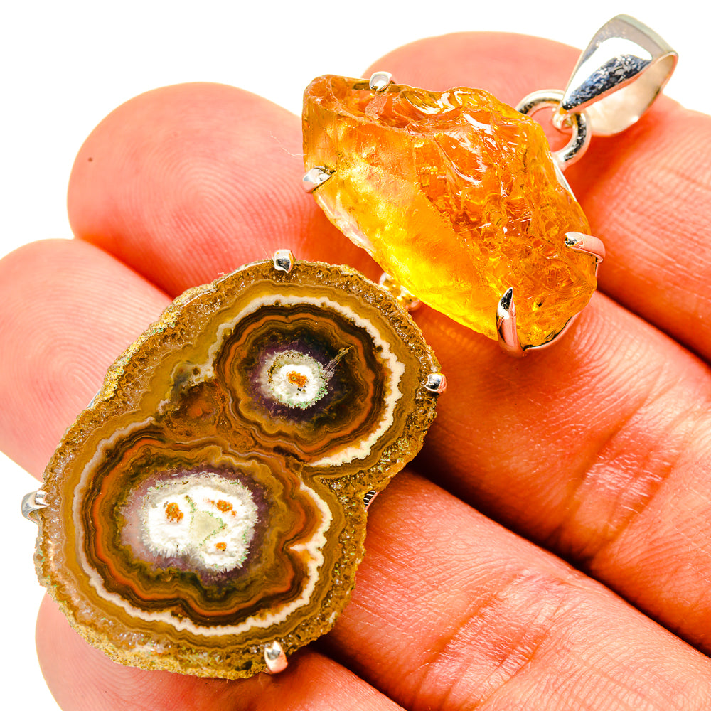 Orange-gold crystal slice pendant in sterling silver setting, shown on fingertip